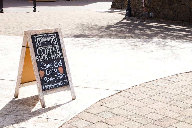 Chalkboard A-frame sign advertising coffee and wine menu at outdoor cafe