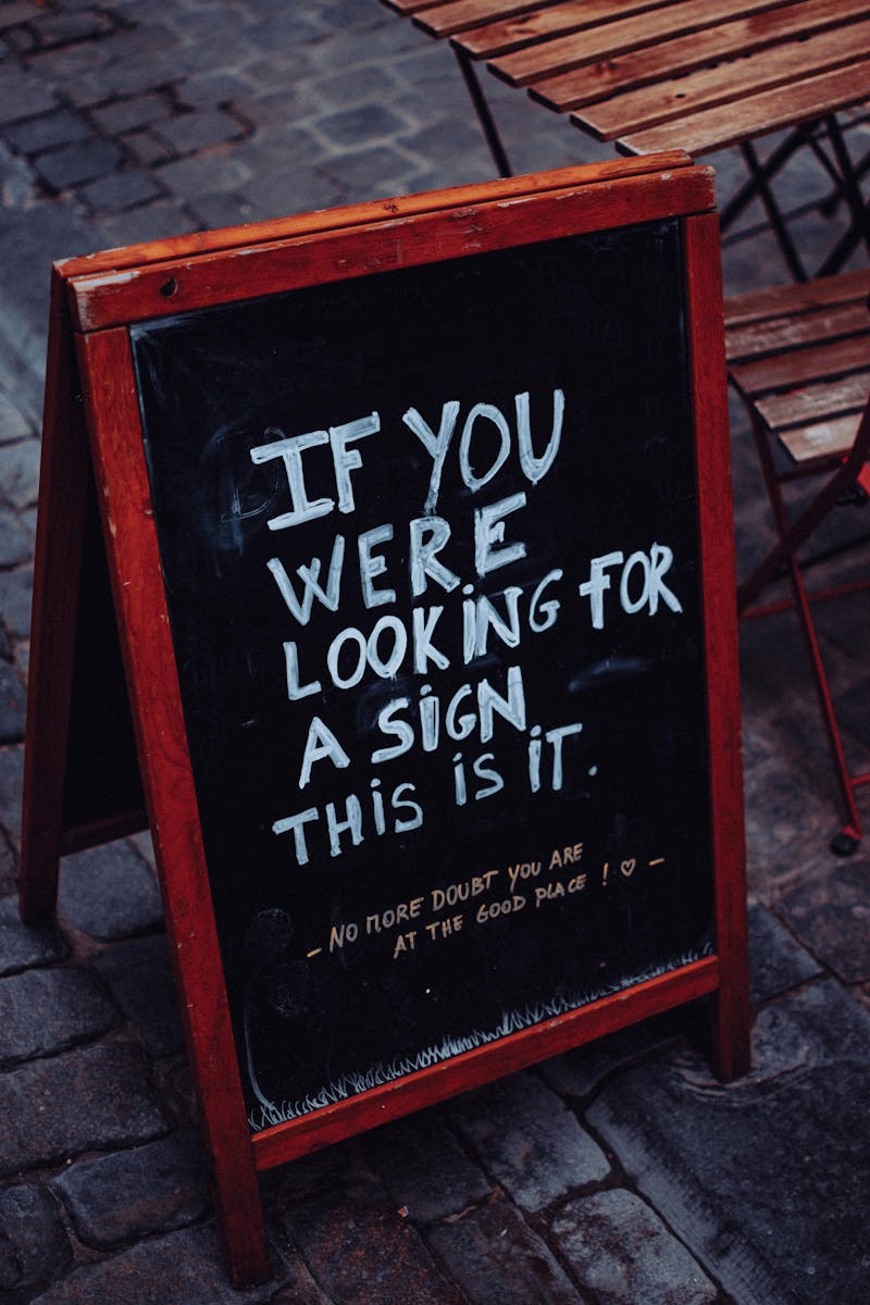 Motivational A-frame chalkboard sign on sidewalk outside a cafe
