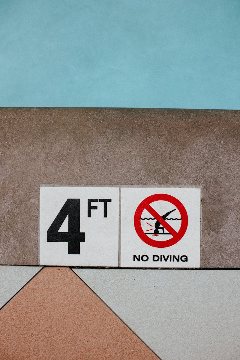 Close-up of 4-foot depth warning and no diving sign at swimming pool edge