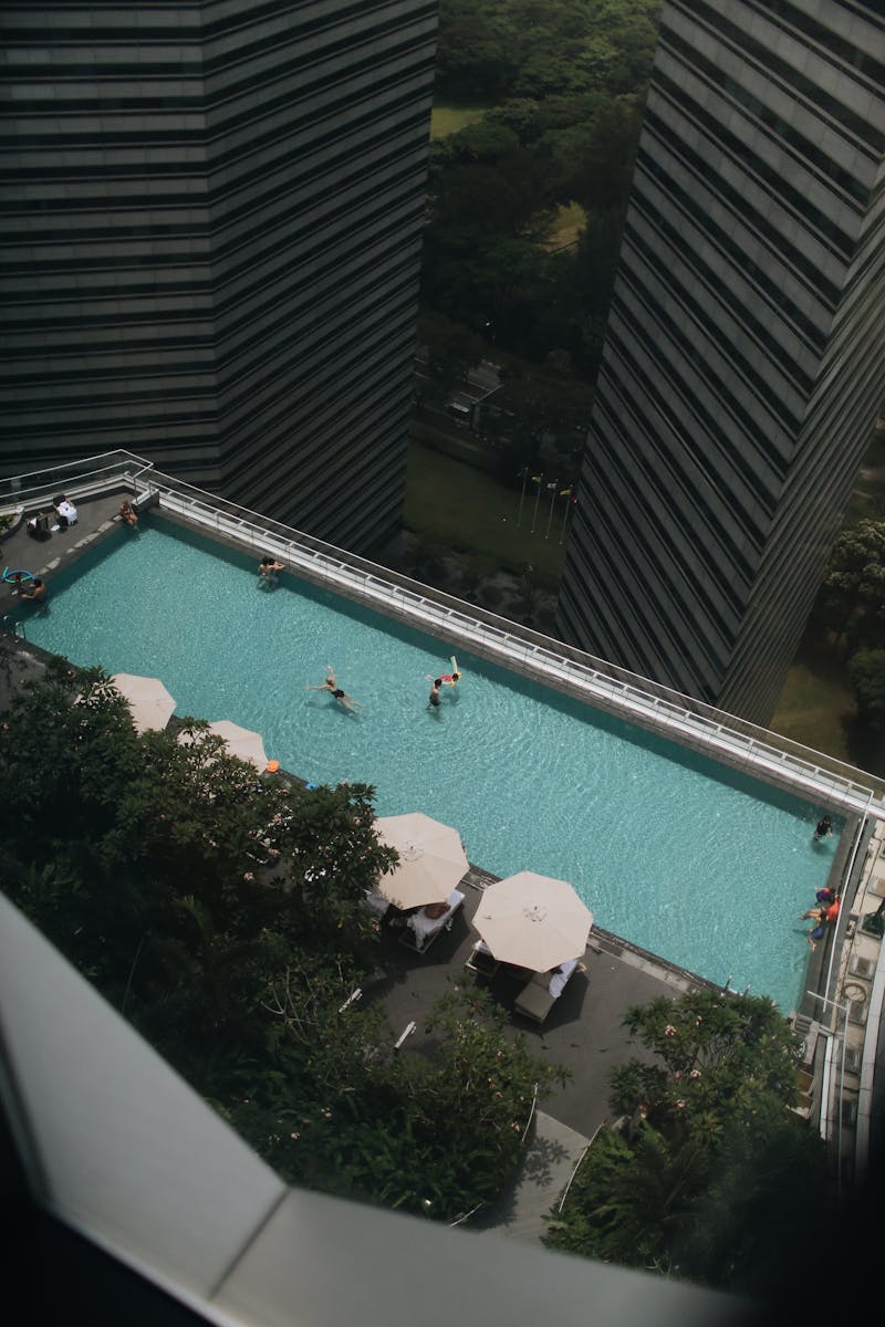 Rooftop swimming pool in city with people swimming surrounded by tall buildings