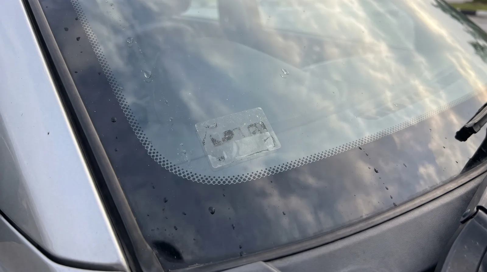 Close-up of an e-hailing sticker in the lower corner of a car front windscreen