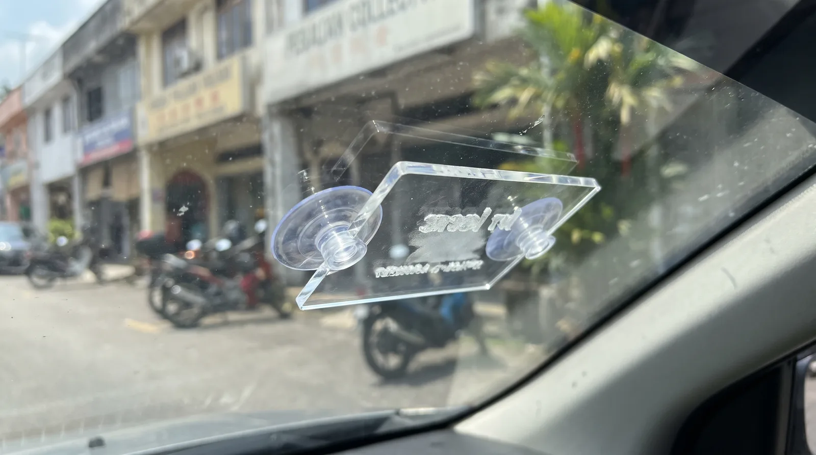 Removable acrylic e-hailing sign with suction cups on a car windscreen