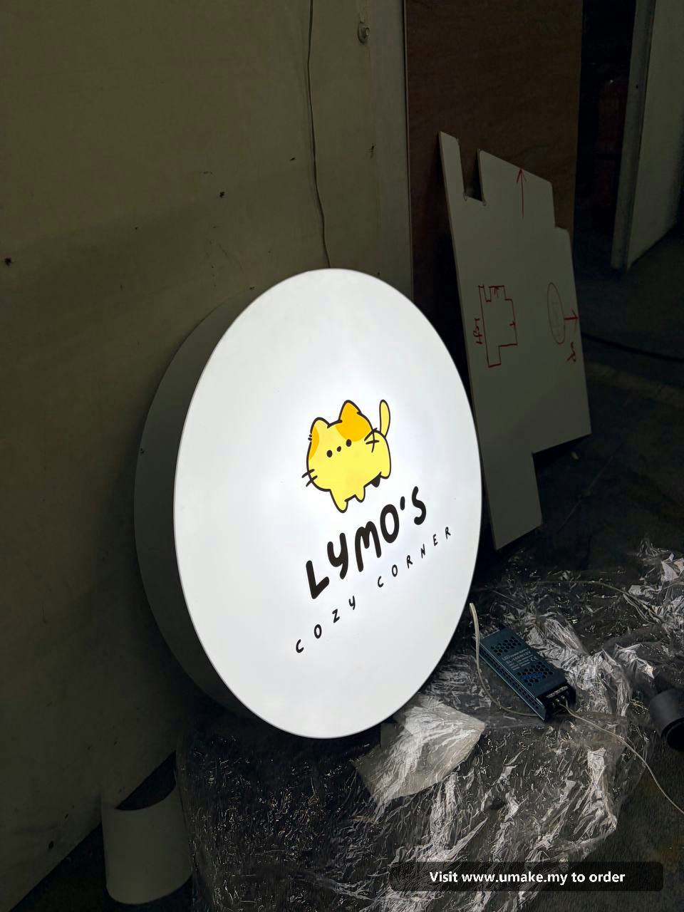 Custom Round LED Lightbox Signboard by UMAKE Malaysia (5) A round, white LED lightbox signboard for 'Lymo's Cozy Corner' featuring a cute yellow cat logo, manufactured by UMAKE Malaysia.