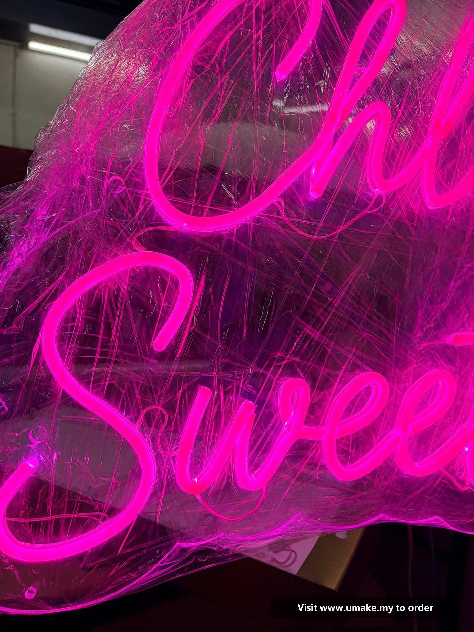 Custom Pink Neon Flex Signage by UMAKE Malaysia Close-up of a custom neon flex sign glowing bright pink, wrapped in protective clear plastic, with a 12V power supply visible.