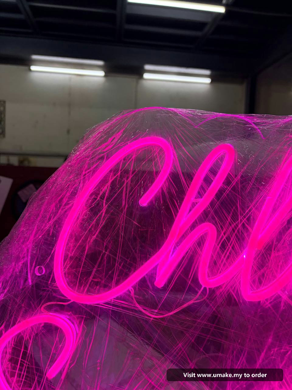 Custom Pink Neon Flex Signage by UMAKE Malaysia (2) Close-up of a custom neon flex sign glowing bright pink, wrapped in protective clear plastic, with a 12V power supply visible.