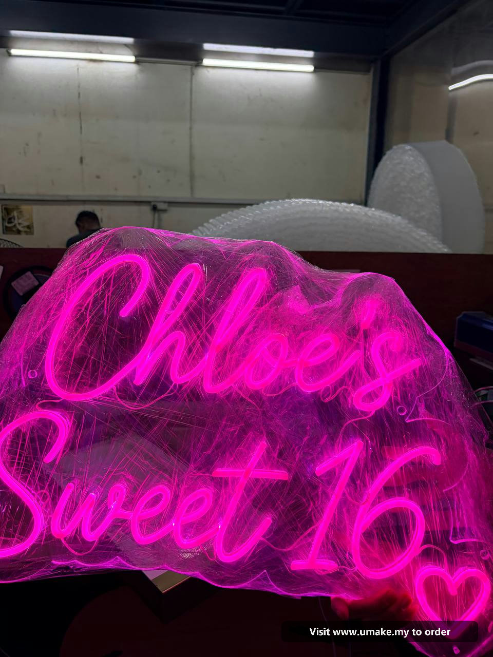 Custom Pink Neon Flex Signage by UMAKE Malaysia (3) Close-up of a custom neon flex sign glowing bright pink, wrapped in protective clear plastic, with a 12V power supply visible.