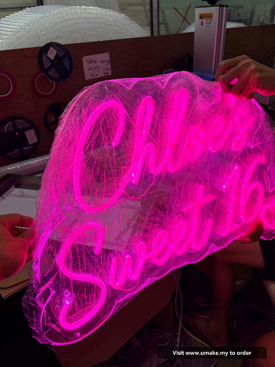 Custom Pink Neon Flex Signage by UMAKE Malaysia (4) Close-up of a custom neon flex sign glowing bright pink, wrapped in protective clear plastic, with a 12V power supply visible.