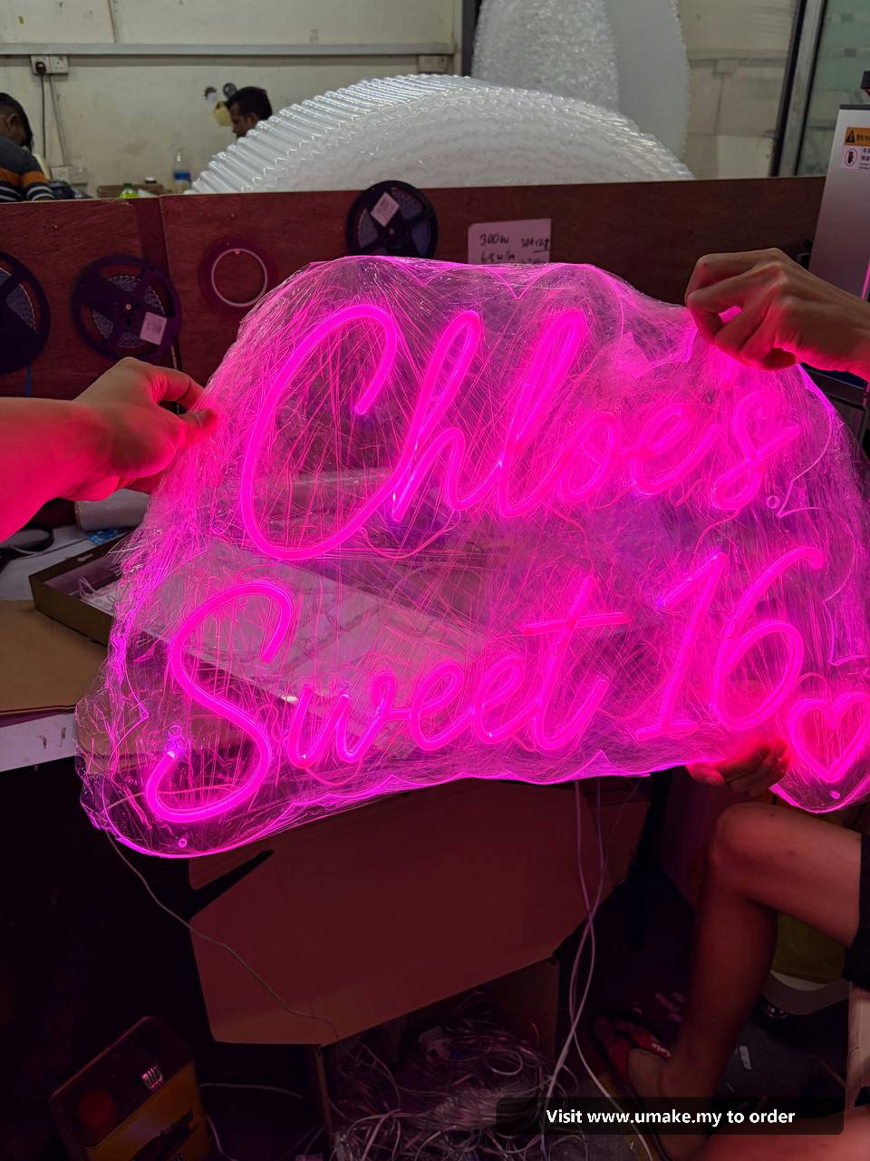Custom Pink Neon Flex Signage by UMAKE Malaysia (5) Close-up of a custom neon flex sign glowing bright pink, wrapped in protective clear plastic, with a 12V power supply visible.