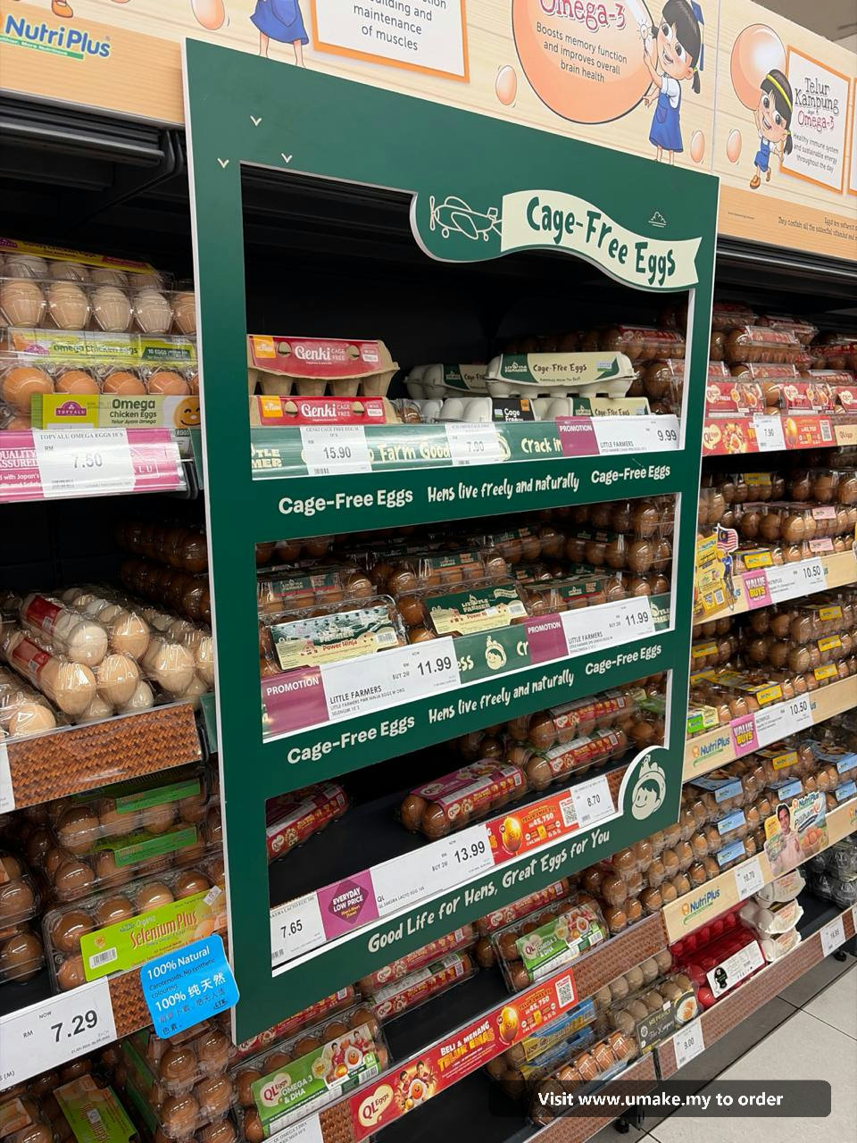 Custom PVC Signage with Sticker Printing by UMAKE Malaysia A custom-cut green PVC signage with 'Cage-Free Eggs' text and graphics, featuring a plane and chickens, installed in a supermarket aisle above egg car