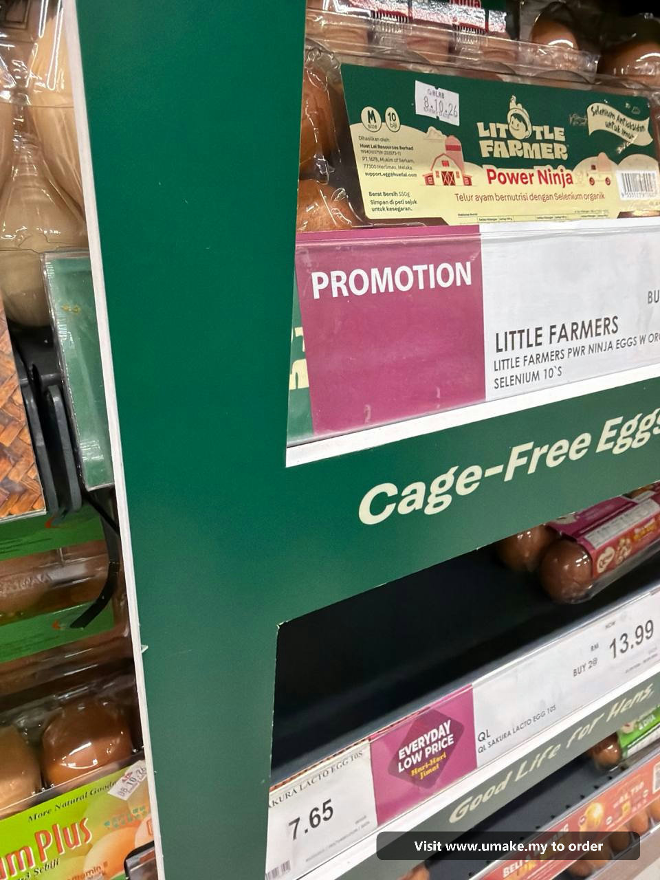 Custom PVC Signage with Sticker Printing by UMAKE Malaysia (3) A custom-cut green PVC signage with 'Cage-Free Eggs' text and graphics, featuring a plane and chickens, installed in a supermarket aisle above egg car