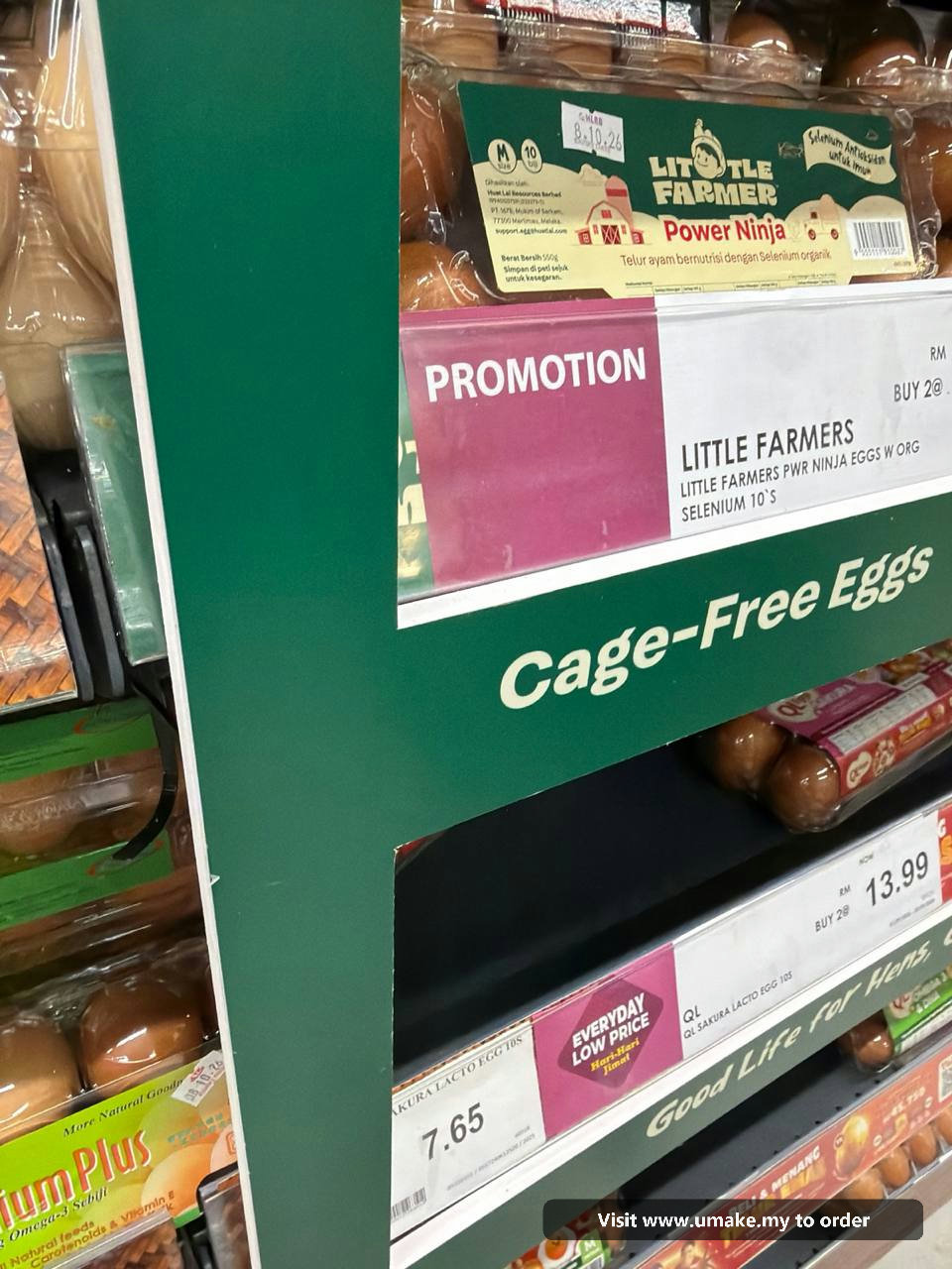 Custom PVC Signage with Sticker Printing by UMAKE Malaysia (4) A custom-cut green PVC signage with 'Cage-Free Eggs' text and graphics, featuring a plane and chickens, installed in a supermarket aisle above egg car