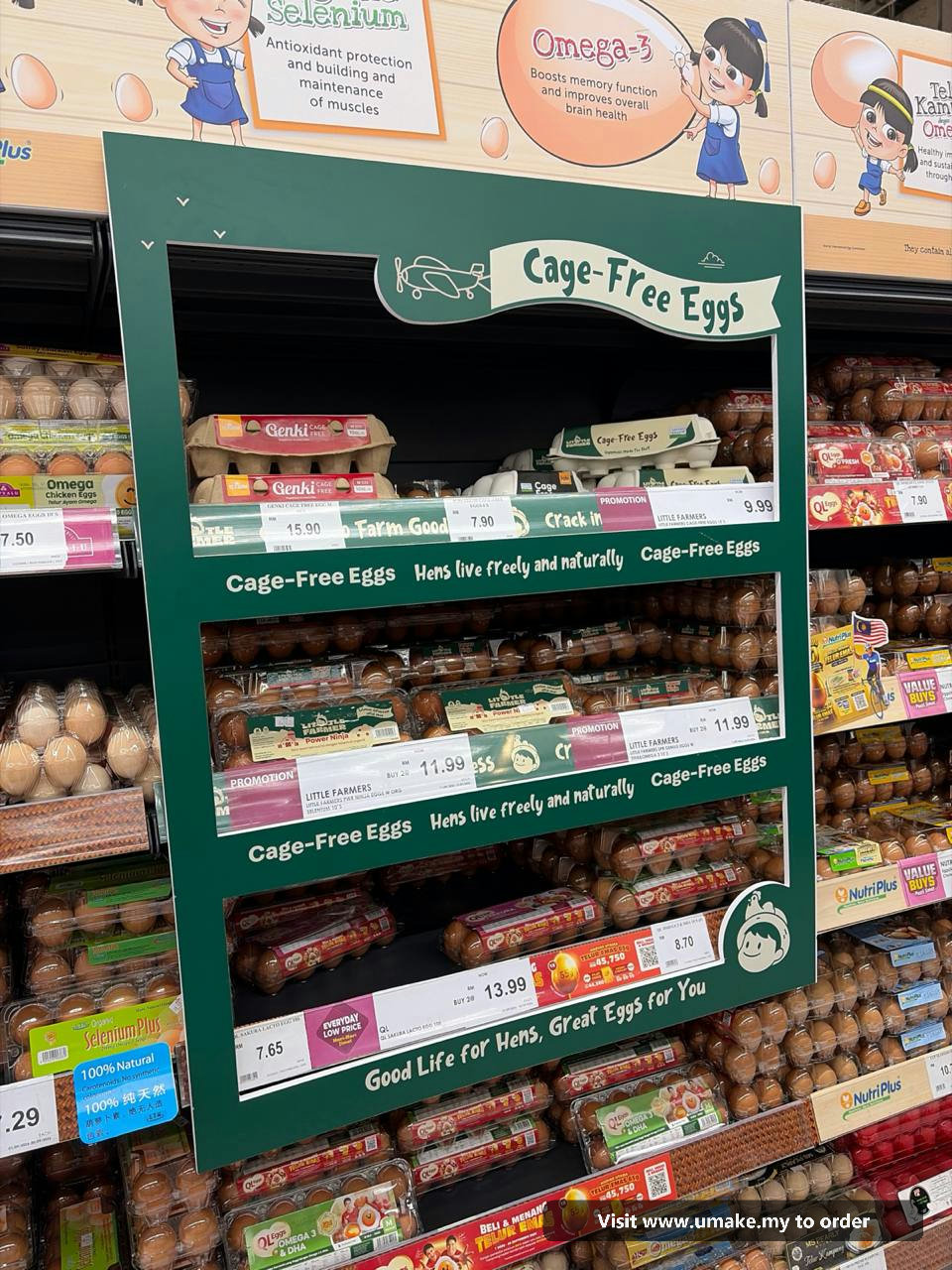 Custom PVC Signage with Sticker Printing by UMAKE Malaysia (5) A custom-cut green PVC signage with 'Cage-Free Eggs' text and graphics, featuring a plane and chickens, installed in a supermarket aisle above egg car