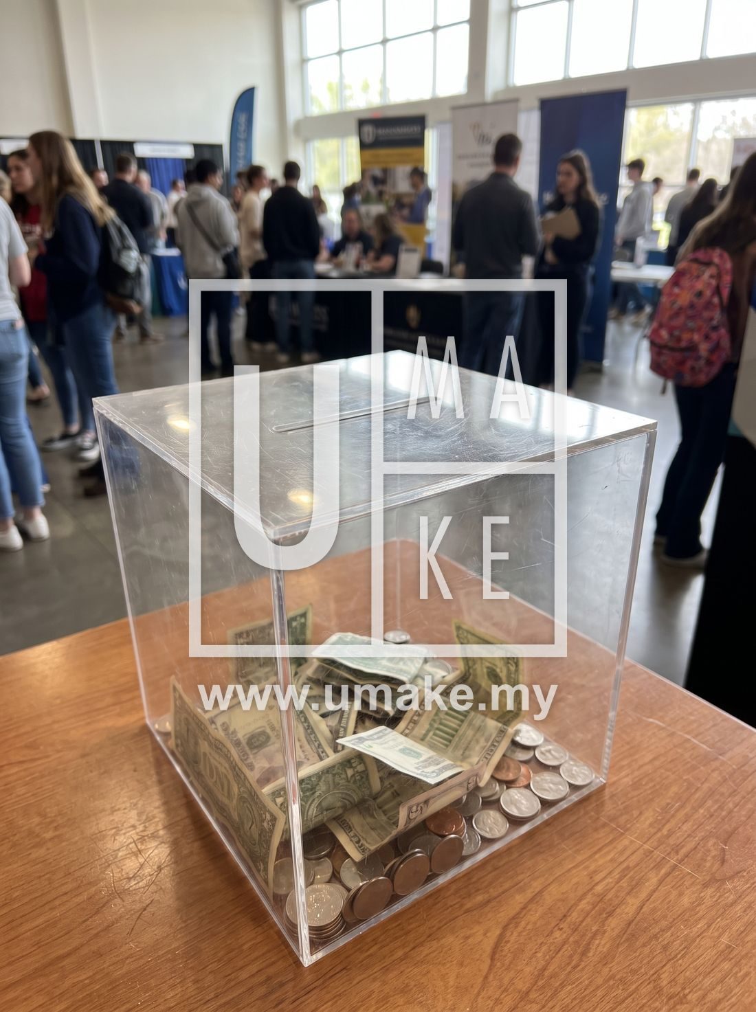Clear acrylic donation box with money on a table at an event