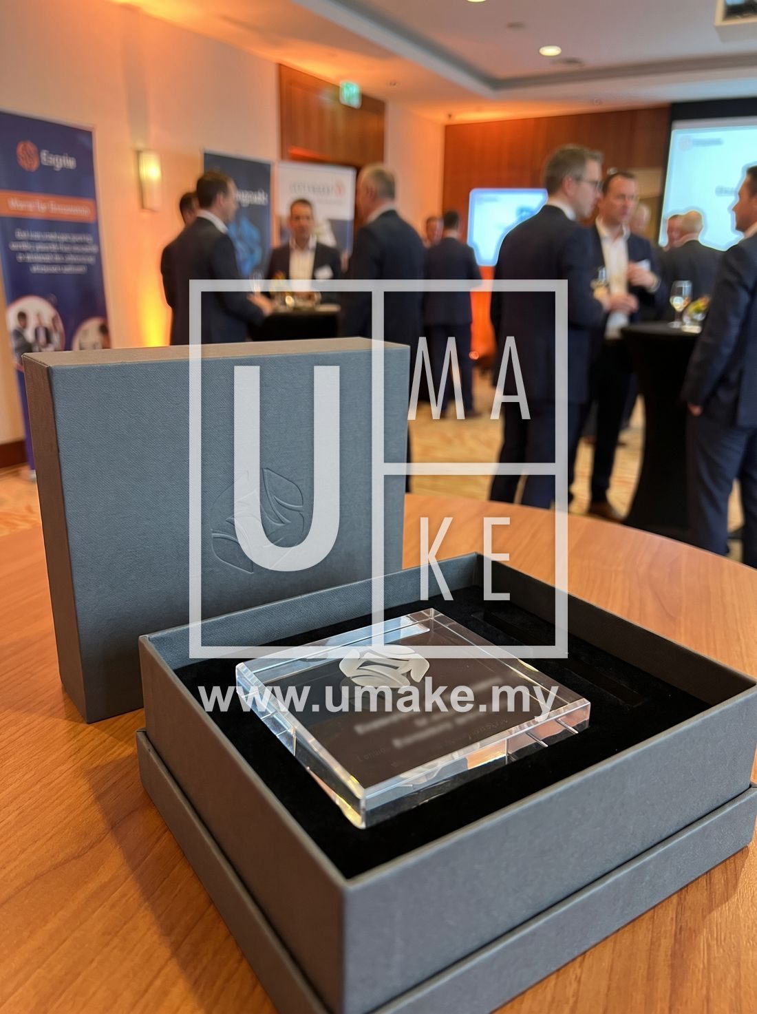A gift box with a branded acrylic desk accessory presented at a corporate event
