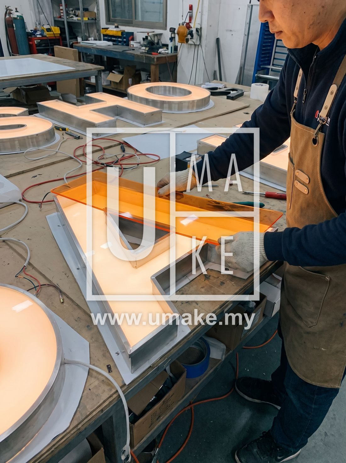A worker applying acrylic face panels onto illuminated channel letters