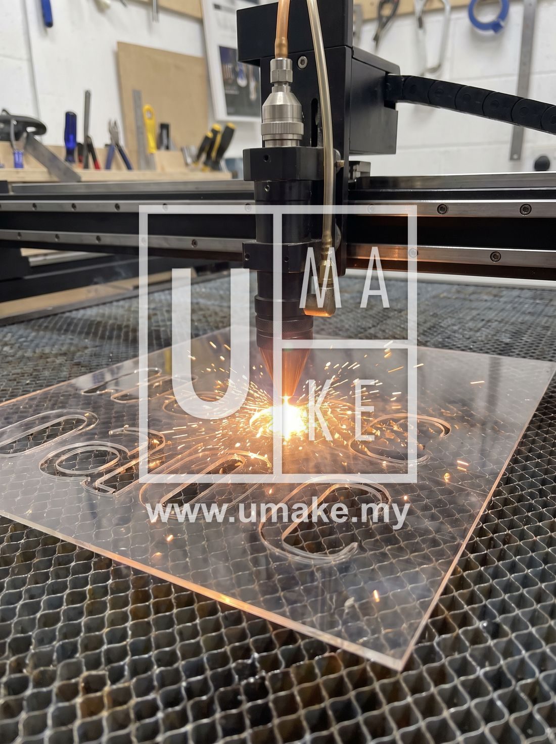 A laser cutting machine cutting acrylic letter shapes with sparks and precision