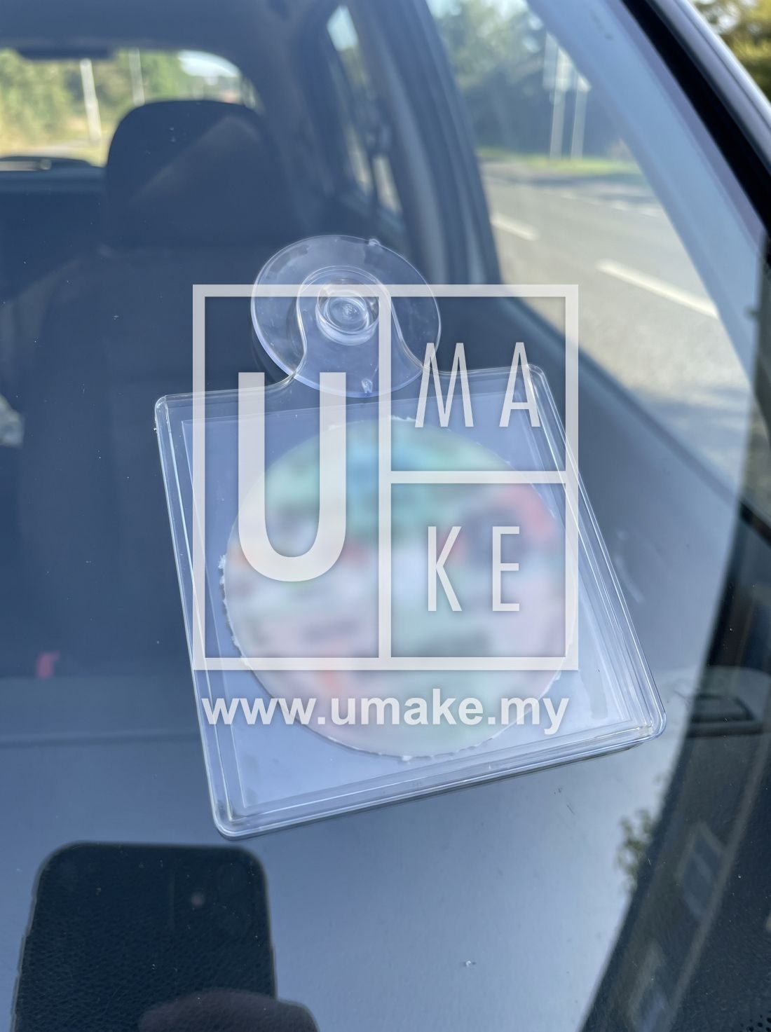 An acrylic road tax holder with a suction cup on glass
