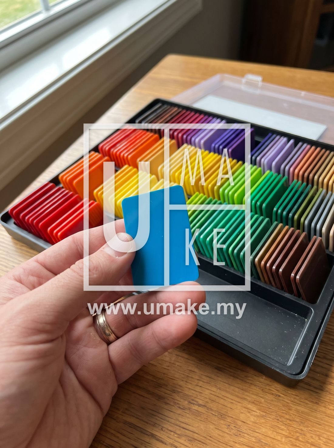 A hand selecting an acrylic colour swatch from a rainbow set