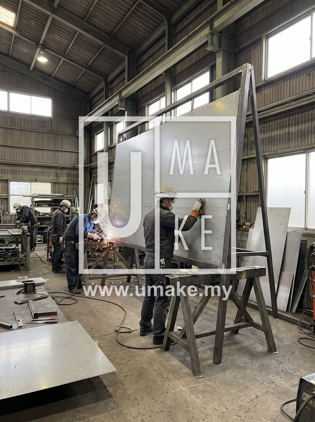 Workers fabricating a large signboard in a factory